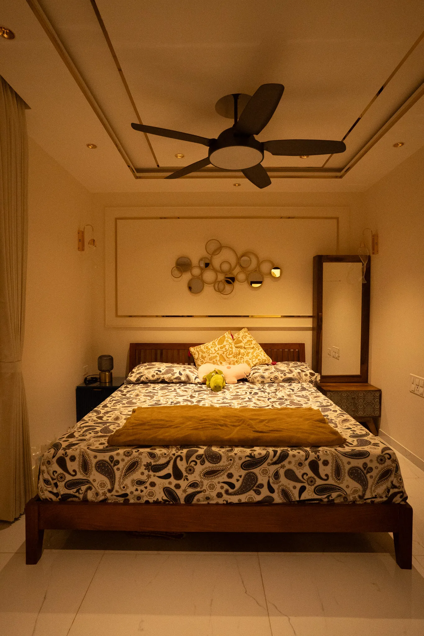 Bedroom with gold disc wall art and layered false ceiling — Divyarjuna
